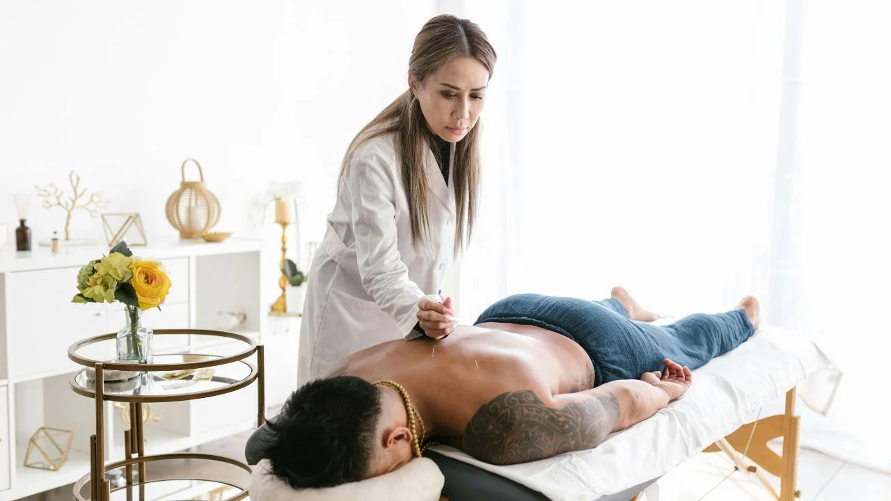 "A peaceful person lying on a therapy bed meditating during an acupuncture session, showing calmness and mind-body balance."