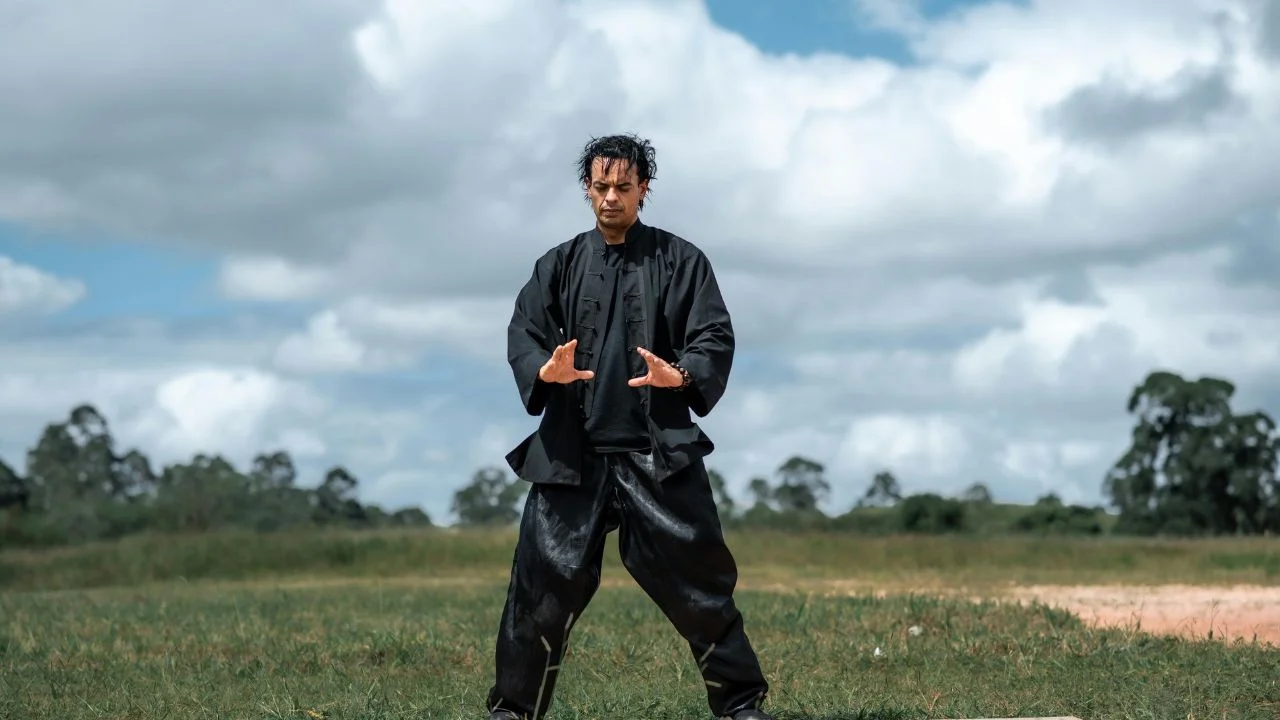Person practicing martial arts meditation in a peaceful outdoor setting, combining focus and movement.